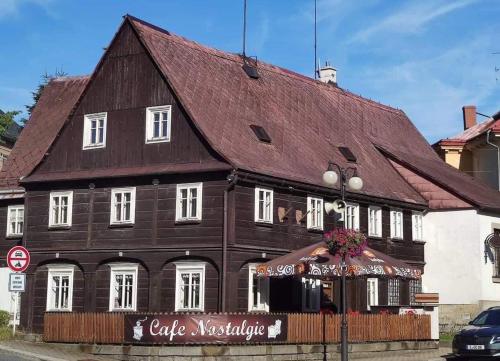 a large wooden building with a brown roof at Cafe Nostalgie dvoulůžkový romantický pokoj in Krásná Lípa