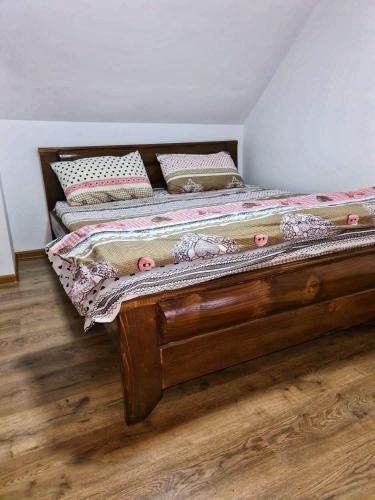 a wooden bed with pillows on it in a room at Cabana Râul Lung in Caransebeş