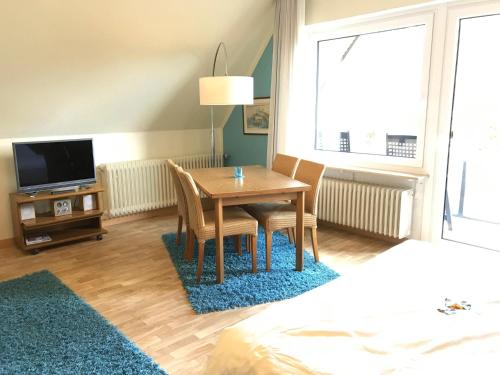 um quarto com uma mesa e cadeiras e uma televisão em Haus am Kurpark - Strandmuschel em Grömitz