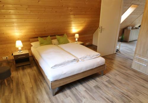 a bedroom with a bed with white sheets and green pillows at Ferienwohnung Seeblick Nr 5, 2 Zi-Bärental, Feldberg in Feldberg