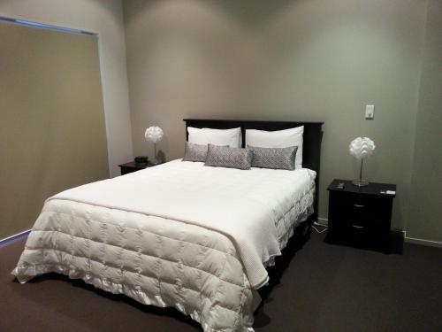 a bedroom with a large bed with white sheets and pillows at Sovereign Pier On The Waterways in Whitianga