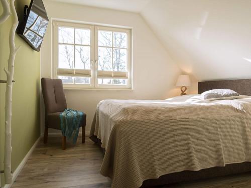 a bedroom with a bed and a chair and a window at Ferienhaus "Zum Achterknoten" in Zingst