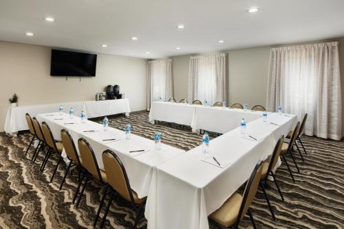 a conference room with tables and chairs and a screen at Staybridge Suites Of Durham - Chapel Hill - RTP by IHG in Durham