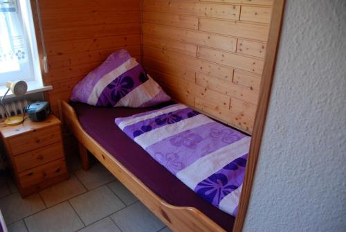 - un petit lit dans une chambre en bois avec des draps violets dans l'établissement Ferienwohnung Cantay - Nr1, à Fehmarn