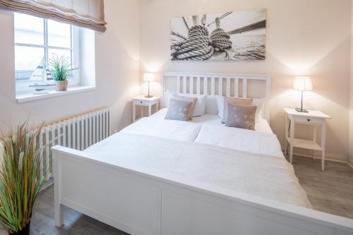 een witte slaapkamer met een groot wit bed en 2 tafels bij Austernfischer in Westermarkelsdorf