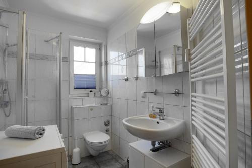 a white bathroom with a sink and a toilet at Sonne, Whg 4 in Zingst