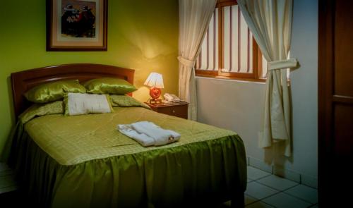 a bedroom with a green bed with two towels on it at HOSTAL MONUMENTAL a Media Cuadra de la Plaza Mayor in Cajamarca