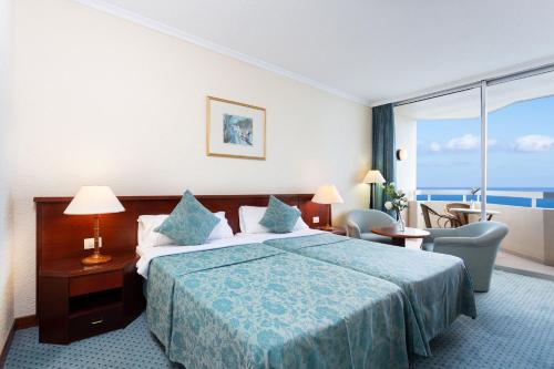 プエルト・デ・ラ・クルスにあるStudio 1509 im Precise Resort Tenerifeのベッドと大きな窓が備わるホテルルームです。