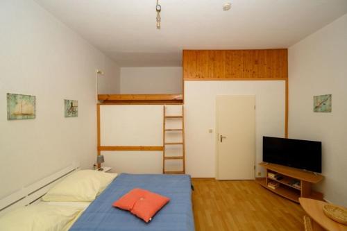 1 dormitorio con 1 cama, TV y escalera en Villa Christiana - Stranddistel en Graal-Müritz