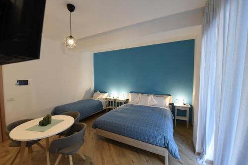 a bedroom with two beds and a table and a blue wall at Geordie's in Potenza