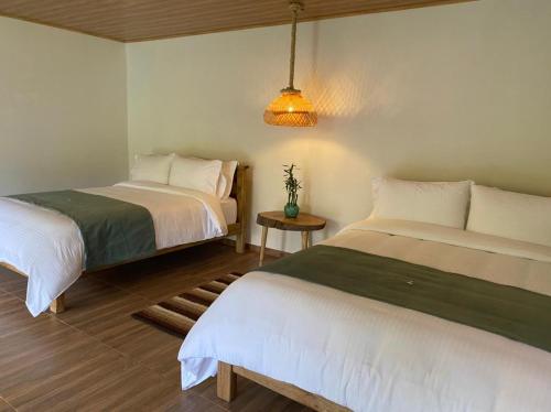 a bedroom with two beds and a table with a lamp at Rancho Ecoturistico el Faro in La Mesa