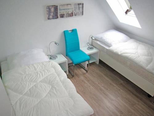 a bedroom with two beds and a blue chair at "Landhaus Voss" Typ 4 Nr12 in Staberdorf