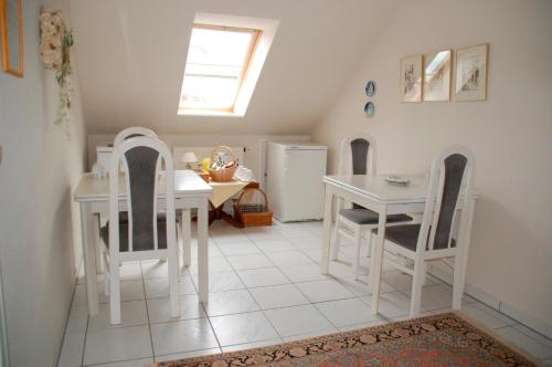 uma cozinha com uma mesa branca e cadeiras, uma mesa e um frigorífico em Privatzimmer Ehrhardt Nr1 em Burg auf Fehmarn