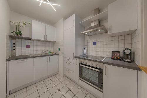 a kitchen with white cabinets and a stove top oven at Appartement 48 Komfort in Wetzlar