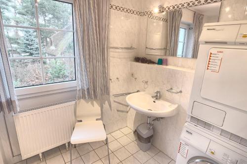 une petite salle de bains blanche avec lavabo et fenêtre. dans l'établissement Strandbiene, à Zingst