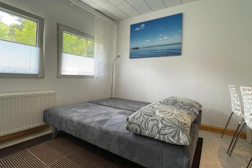 ein kleines Bett in einem Zimmer mit zwei Fenstern in der Unterkunft Steinhuder Meer Ferienhaus Schwalbennest in Neustadt am Rübenberge