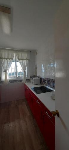 une cuisine avec des placards rouges et un comptoir blanc dans l'établissement Primera línea de playa. Magnífica urbanizacion, à Cala del Moral