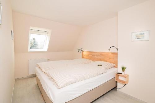 een witte slaapkamer met een groot bed en een raam bij D3 - Haus Dünenpark Königsberger Allee 12 - FERIENDOMIZIL HOLLICH in Grömitz