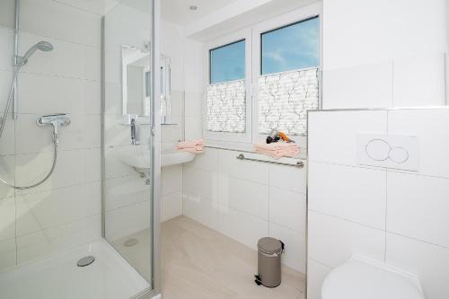 een witte badkamer met een douche en een wastafel bij D3 - Haus Dünenpark Königsberger Allee 12 - FERIENDOMIZIL HOLLICH in Grömitz