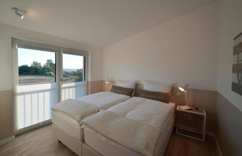 ein Schlafzimmer mit einem großen Bett und einem großen Fenster in der Unterkunft Langeland in Kronsgaard