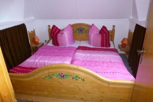 um quarto com uma cama de madeira com lençóis e almofadas cor-de-rosa em Heublein em Poseritz