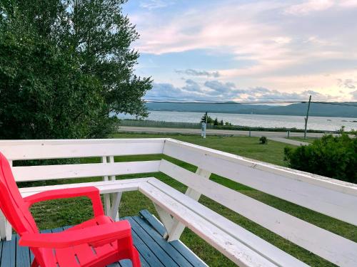 two red chairs sitting on a bench overlooking the water at Sea Breeze Cottages in Ingonish