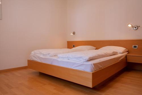 1 dormitorio con cama de madera con sábanas blancas en Ferienwohnung im Haus Texel V, en Rablà