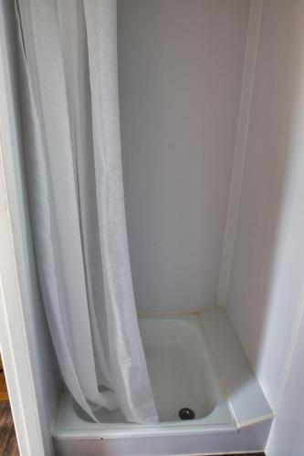 eine Dusche mit einem weißen Duschvorhang neben einer Dusche in der Unterkunft Finnenhaus 3 in Lübeck