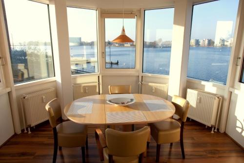 stół i krzesła w pokoju z oknami w obiekcie Apartment 8 w mieście Wilhelmshaven