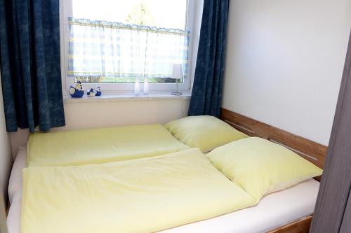 uma cama com lençóis amarelos num quarto com uma janela em Fewo 91 WHG A 5 in Burhave em Burhave
