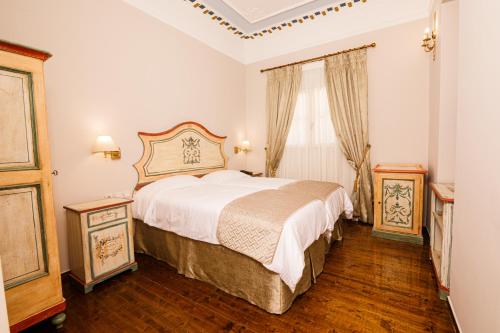 1 dormitorio con 1 cama grande y 2 mesitas de noche en Palaiologos Luxury City Hotel, en Patra