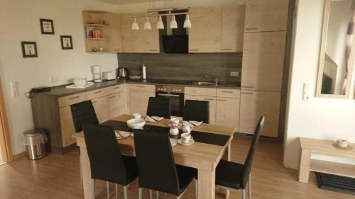 uma cozinha com uma mesa de madeira e cadeiras pretas em FeWo1 Griese em Damnatz