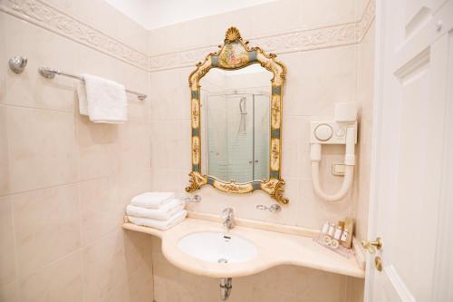 a bathroom with a sink and a mirror at Palaiologos Luxury City Hotel in Patra