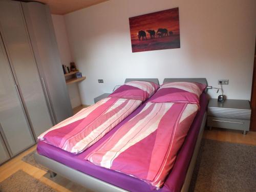 Una cama en un dormitorio con una manta rosa y blanca en Ferienwohnung Iris en Fritzlar