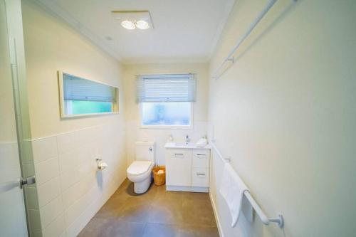 a bathroom with a toilet and a sink and a window at 150 Steps FREE WI-FI in Apollo Bay