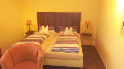 ein Hotelzimmer mit 2 Betten und einem Stuhl in der Unterkunft Ferienwohnung Klein in Bad Zwischenahn