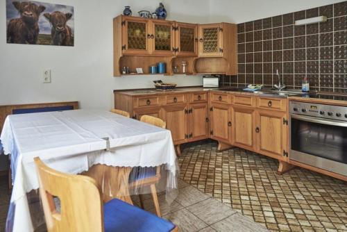 une cuisine avec des placards en bois et une table avec des chaises dans l'établissement Fewo Bubenberg, à Bad Berleburg