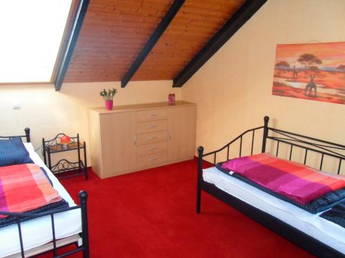 two beds in a room with a red carpet at Ferienwohnung Schulz in Heiligenhafen