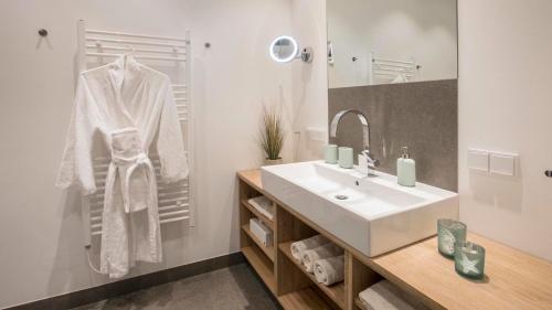 Baño blanco con lavabo y espejo en SPA Apartment FIRST Sellin, en Ostseebad Sellin