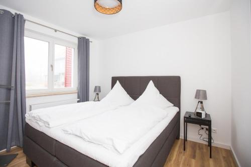 1 dormitorio con 1 cama con sábanas blancas y ventana en Ferienwohnung PlauOase en Plau am See