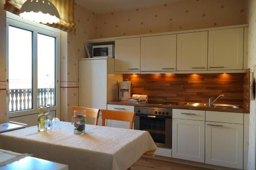 eine Küche mit einem Tisch und eine Küche mit weißen Schränken in der Unterkunft Haus Hansen - Wyk Whg 01 in Wyk auf Föhr