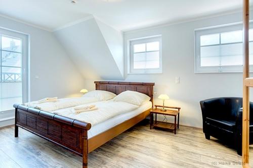 um quarto com uma cama, uma cadeira e janelas em Villa Arielle, FW 8 em Zingst