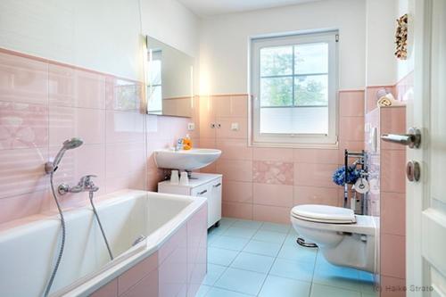 uma casa de banho cor-de-rosa com um lavatório e um WC. em Villa Arielle, FW 8 em Zingst