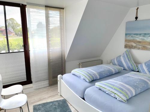 een slaapkamer met een bed met blauwe kussens en een raam bij FeWo Seegras in Grödersby