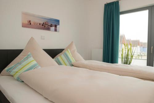 two white beds in a room with a window at Ostsee - Appartement Nr 87a "Strandkorb" im Strand Resort in Heiligenhafen