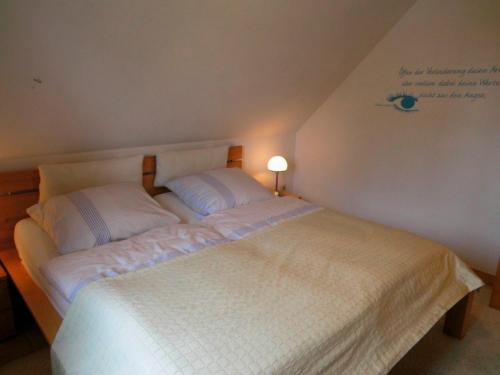 a bedroom with a white bed with two pillows at Ferienwohnung Lindenstraße in Heiligenhafen