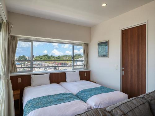 a bedroom with two beds and a large window at Seaside Condominium Rana Chatan in Chatan