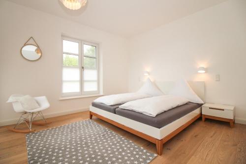 ein Schlafzimmer mit einem Bett, einem Stuhl und einem Fenster in der Unterkunft DeichGalerie89 - a48723 in Krummhörn