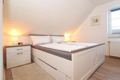 um pequeno quarto com uma cama branca e uma janela em Muckelstuuv in Greetsiel em Greetsiel