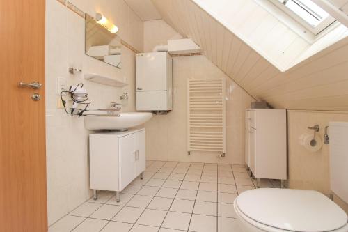 uma casa de banho com um WC, um lavatório e uma clarabóia em Muckelstuuv in Greetsiel em Greetsiel